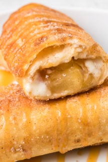 Close up of an apple cheesecake chimichanga that has been cut open on the end to show the cream cheese and apple pie filling