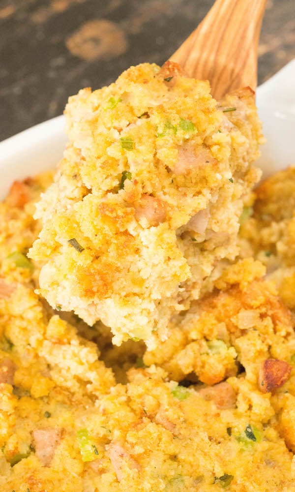 A wooden serving spoon full of cornbread stuffing