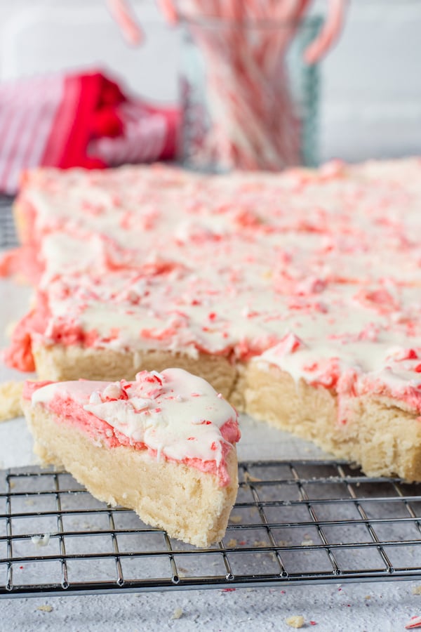 A slab of candy cane cookie bars with one piece cut out in a triangle shape.