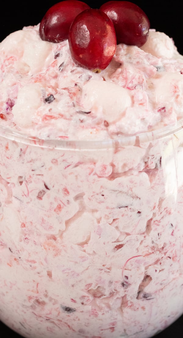 Close up of cranberry fluff dessert in a stemless wine glass on a black background