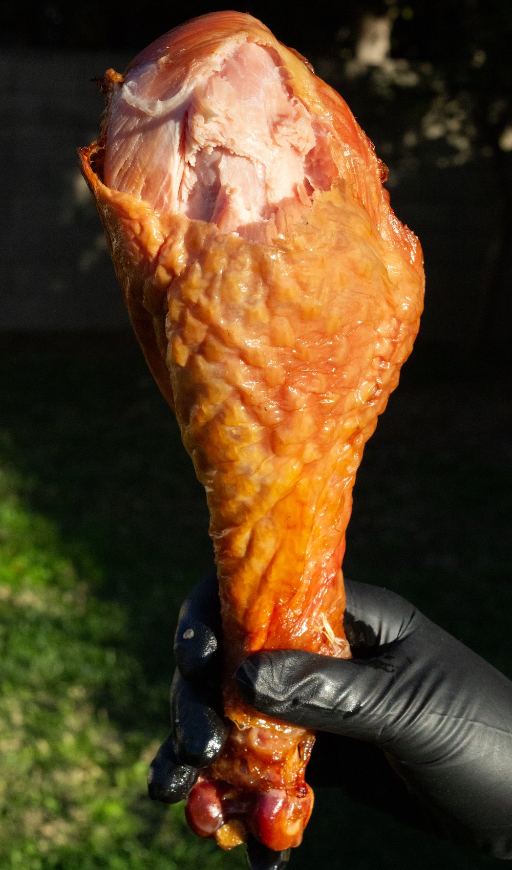 A hand with a black glove on holds up a cooked copycat Disney turkey leg that has a bite taken out of it
