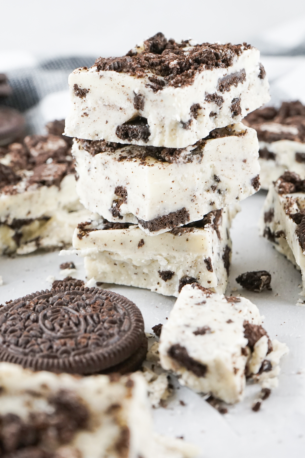 Three pieces of cookies and cream fudge stacked on one another on a white background