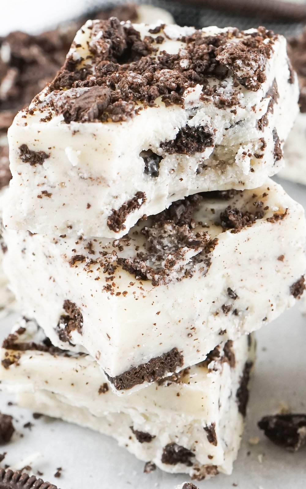 Close up of three pieces of cookies & cream fudge stacked on each other - the top has a bite taken out of it