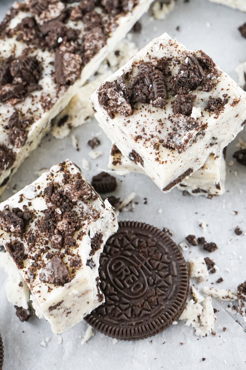 Overhead shot of two pieces of cookies and cream fudge and an Oreo cookie on a white background