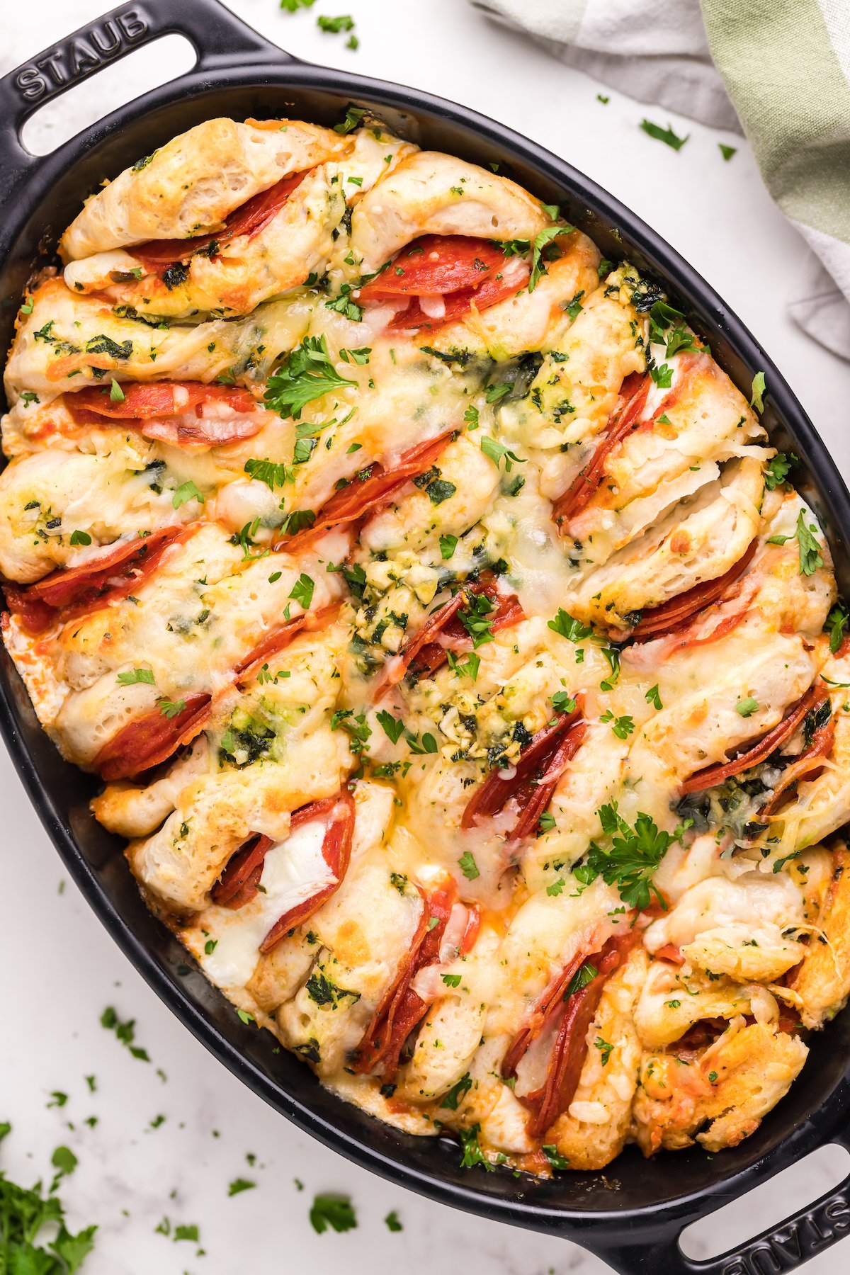 An oval casserole dish that's filled with canned biscuits stuffed with pizza toppings to make a casserole.