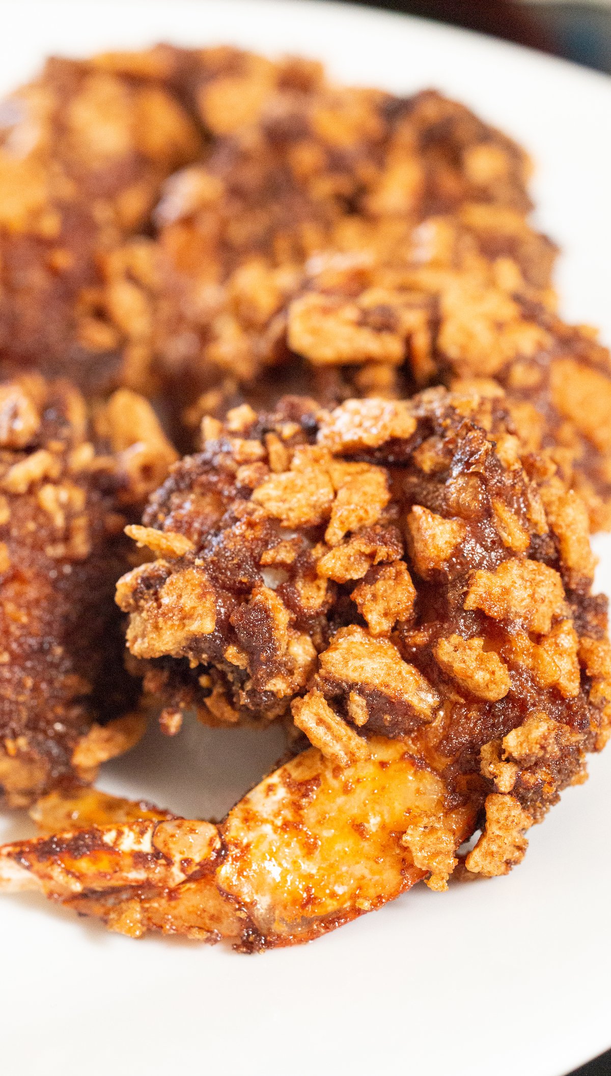 Close up of a cinnamon toast crunch shrimp on a white plate.