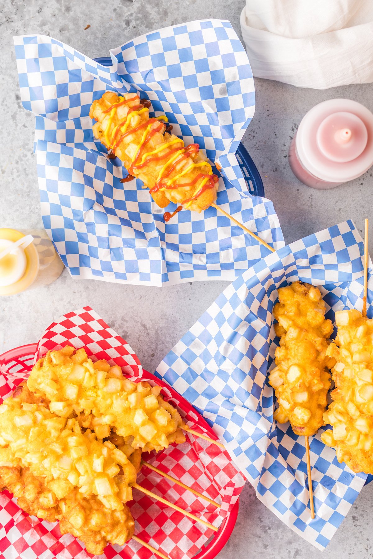 Overhead shot of three plastic food baskets full of french fry coated corn dogs.