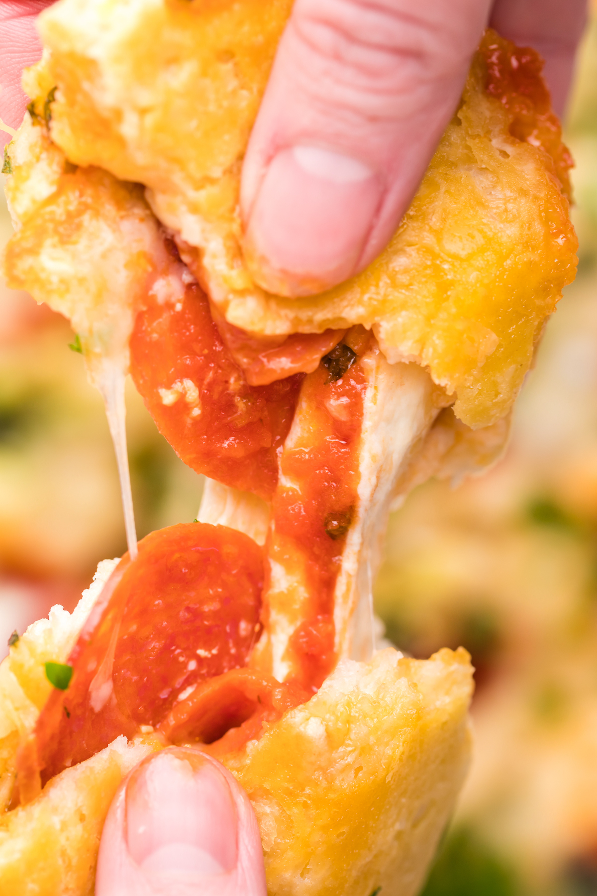 Close up of a cooked canned biscuit filled with cheese and pepperonis being pulled apart. 