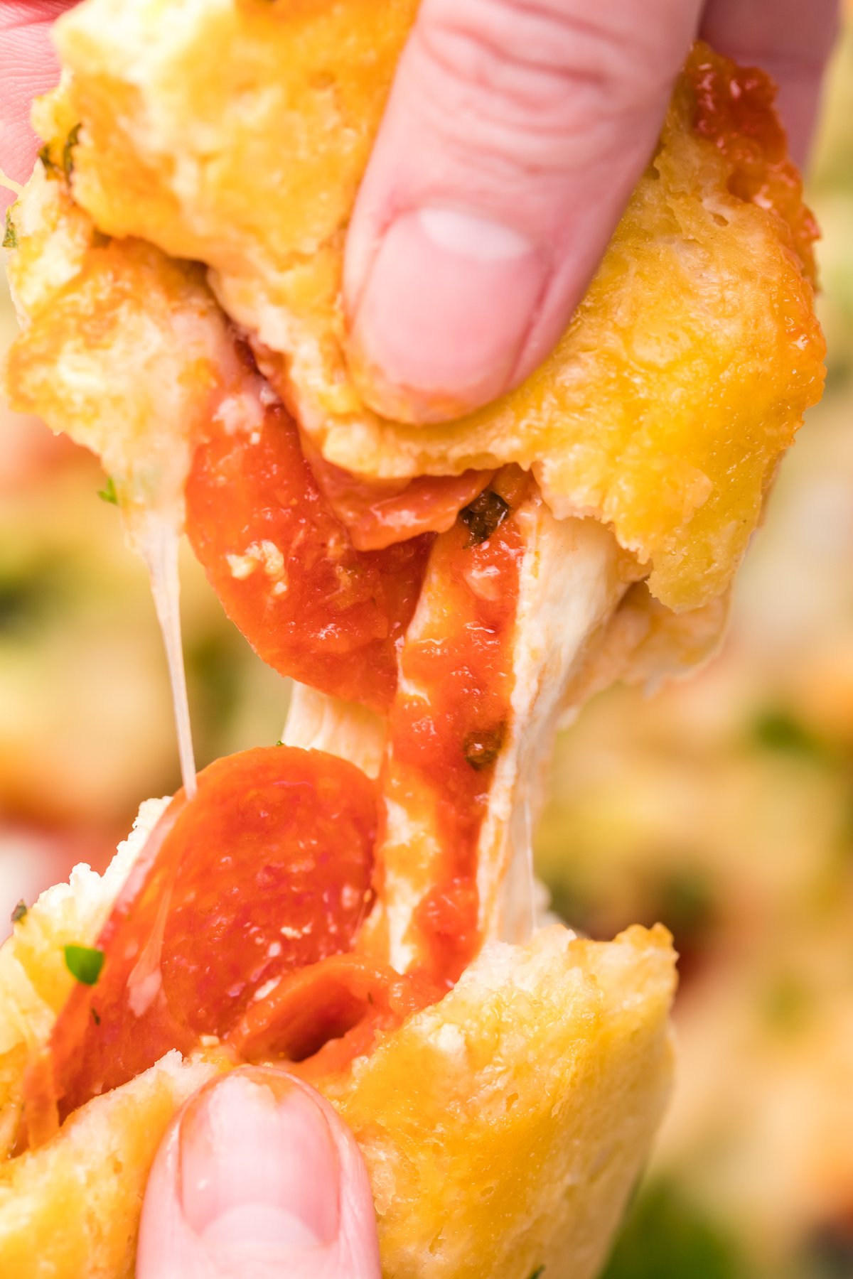 Close up of a cooked canned biscuit filled with cheese and pepperonis being pulled apart. 