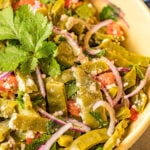 Prepared cactus salad topped with cilantro sits in a yellow serving bowl