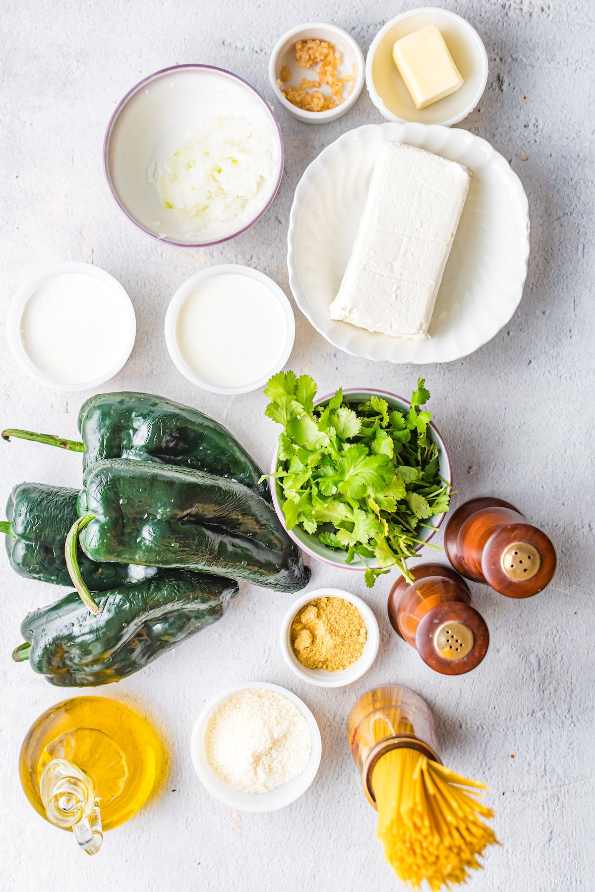 Overhead shot of the ingredients you need to make green Mexican spaghetti. Fresh poblanos, cream cheese, cilantro, noodles, salt, pepper, and oil.