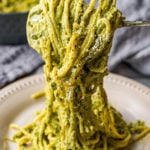 A fork twirls green Mexican spaghetti over a plate