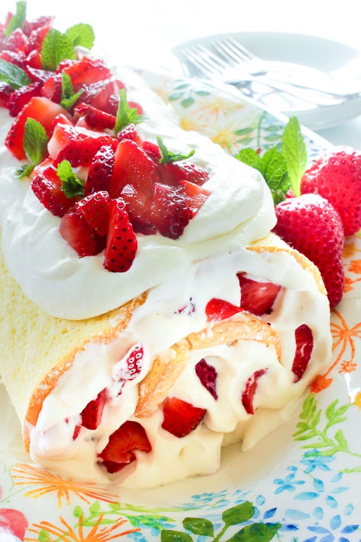 A yellow cake roll filled with cream & strawberries and also topped with strawberries and whipped cream.