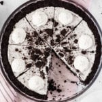 Overhead view of a cookies & cream oreo pie in a glass pie dish. A slice has been removed.