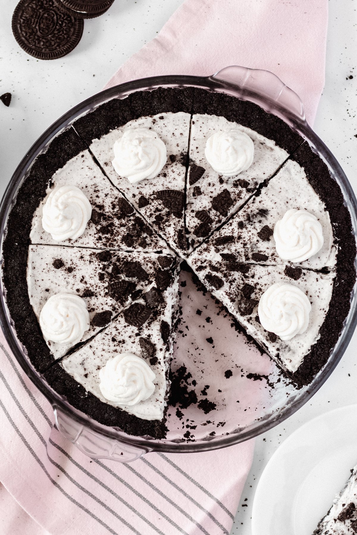 Overhead view of a cookies & cream oreo pie in a glass pie dish. A slice has been removed.