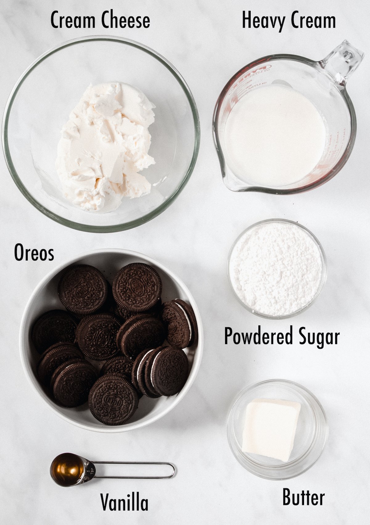 Overhead view of the ingredients needed for cookies and cream pie: cream cheese, heavy cream, oreos, powdered sugar, vanilla, and butter