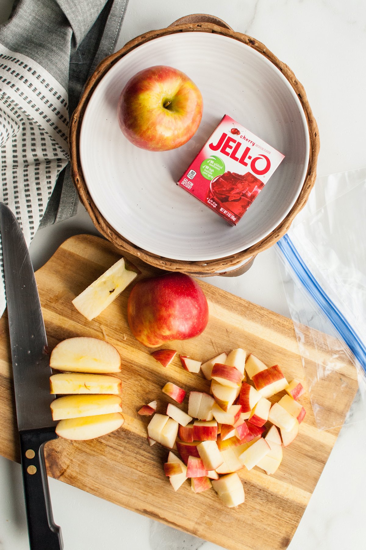 Overhead view of chopped apples on a cutting board next to a box of Jello