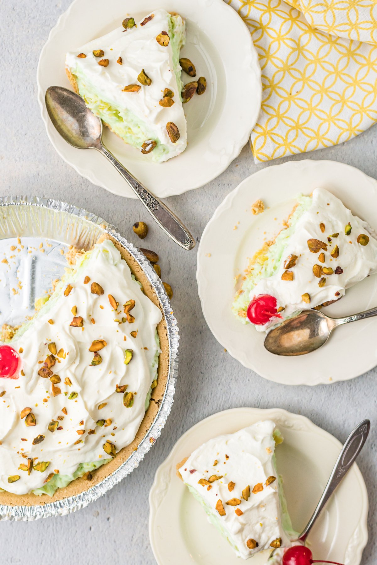 Overhead view of three slices of pistachio pie on serving plates next to the cut pie.