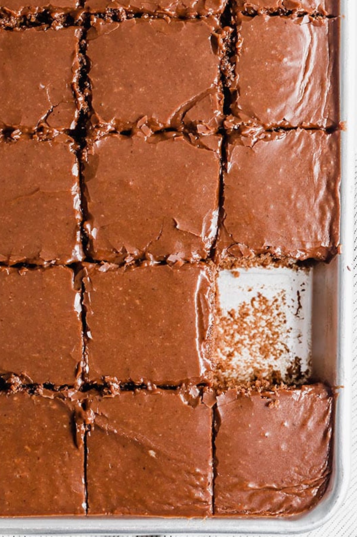 Overhead view of a chocolate Texas Sheet Cake that's been cut into square slices.