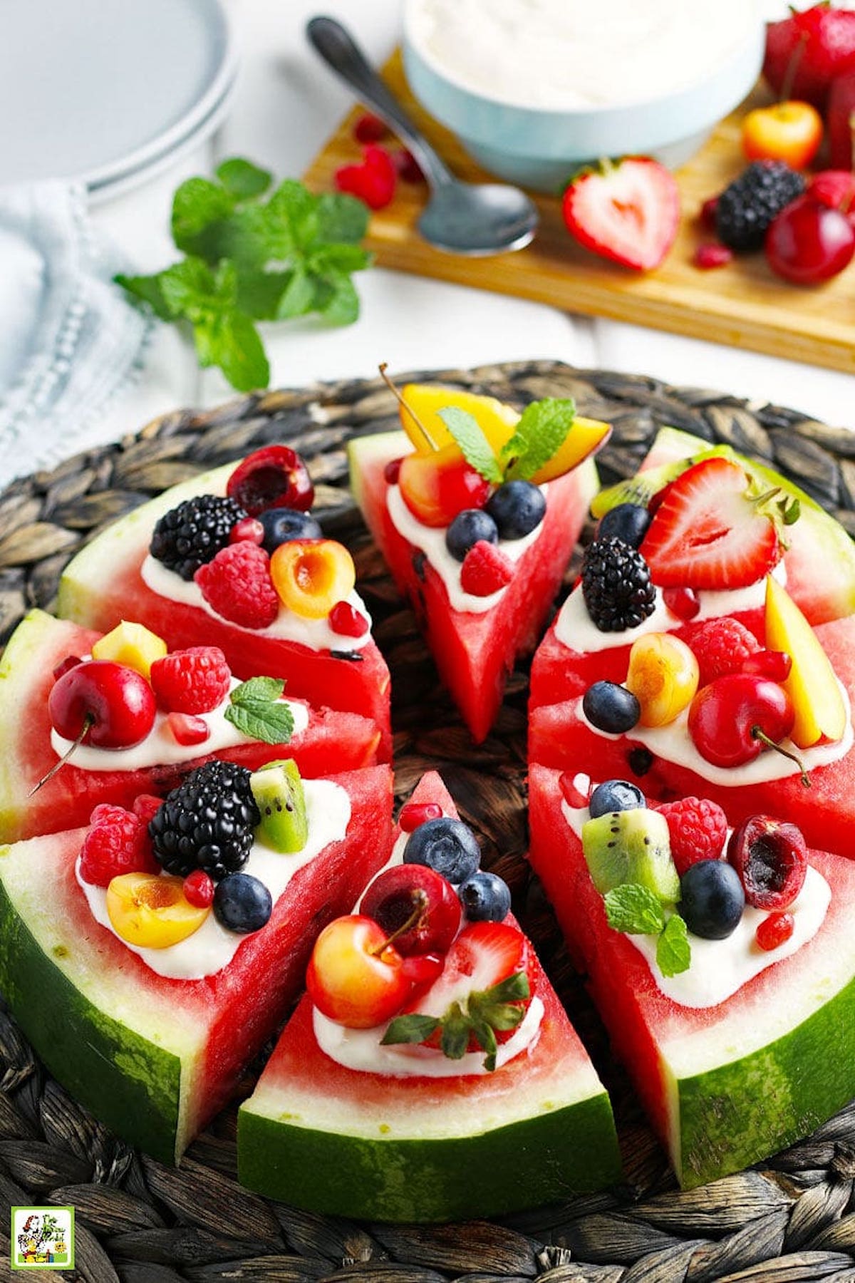 Eight watermelon slices are in the shape of a pizza. Each slice is topped with Greek yogurt then fresh fruit.