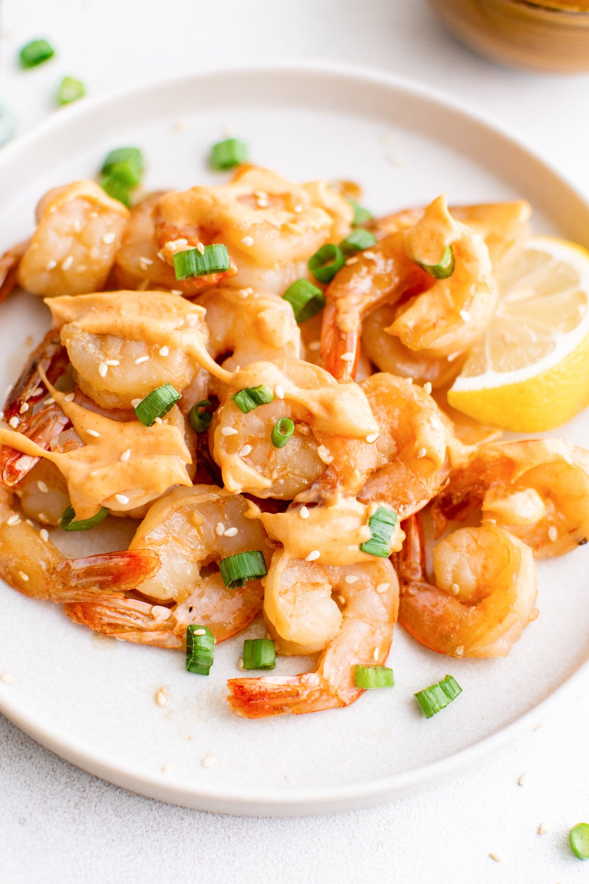 A white dinner plate filled with hibachi shrimp that's been drizzled with yum yum sauce.