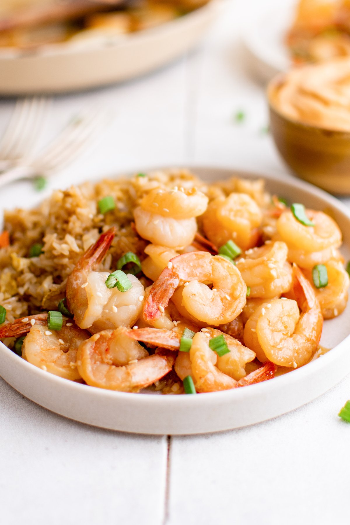 A white serving plate filled with hibachi shrimp. A bowl of yum yum sauce sits in the background.