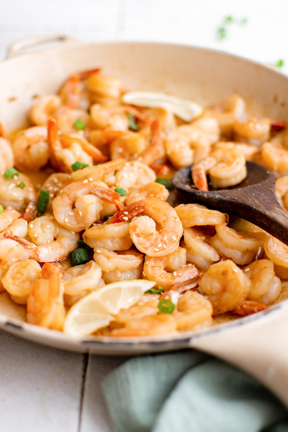 A large pan filled with cooked hibachi shrimp that's garnished with sliced green onions and sesame seeds.