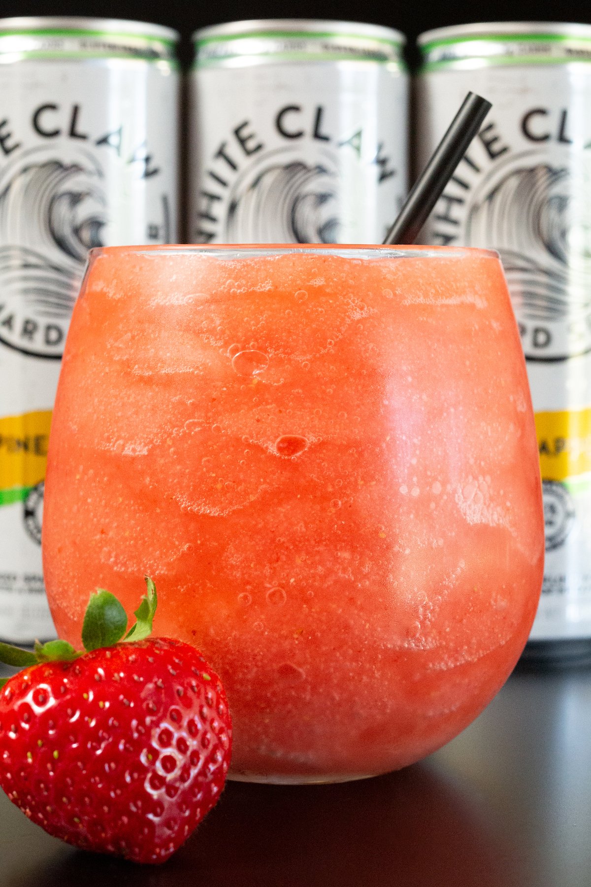 Closeup of a wine glass filled with a pink colored white claw slushie.