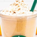 Close up of a starbucks plastic tumbler with a pumpkin spice frappucino and whipped cream on top.