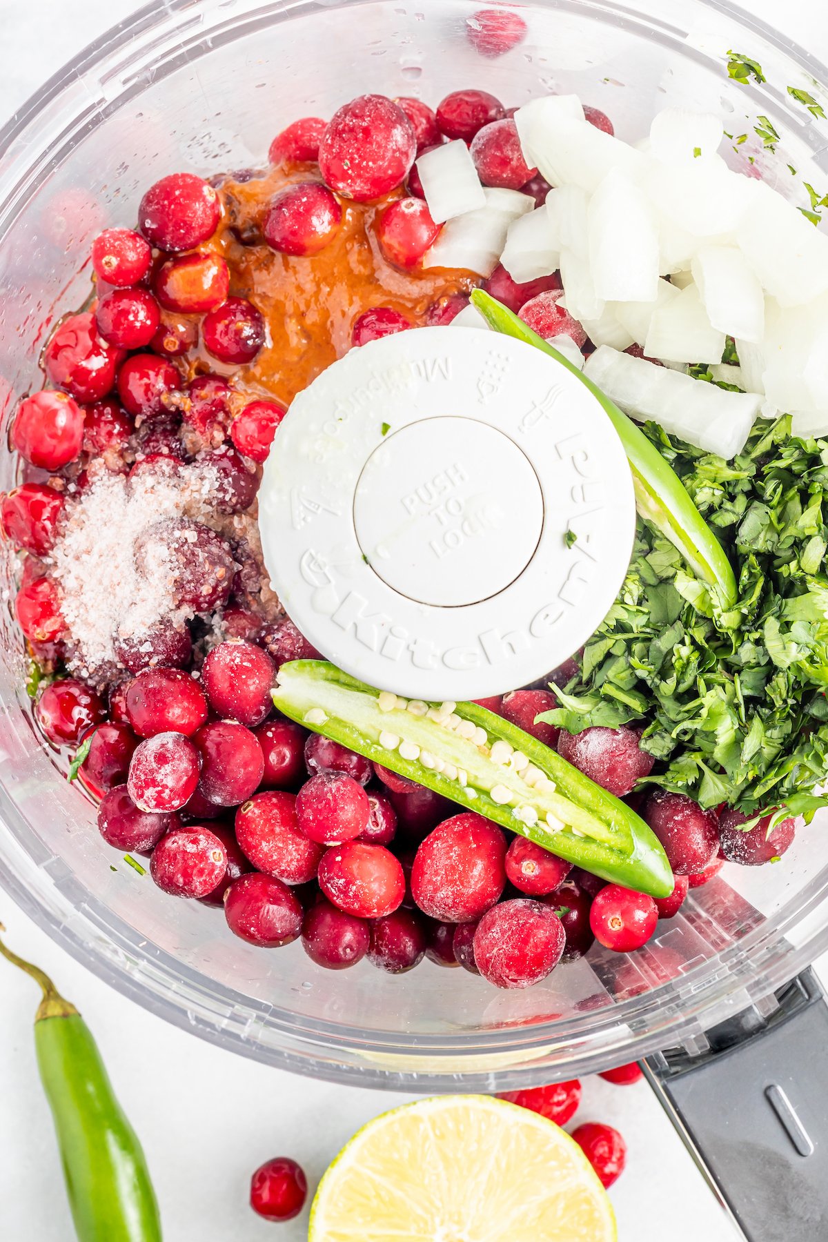 Overhead view of cranberry salsa ingredients in a food processor before being pureed.