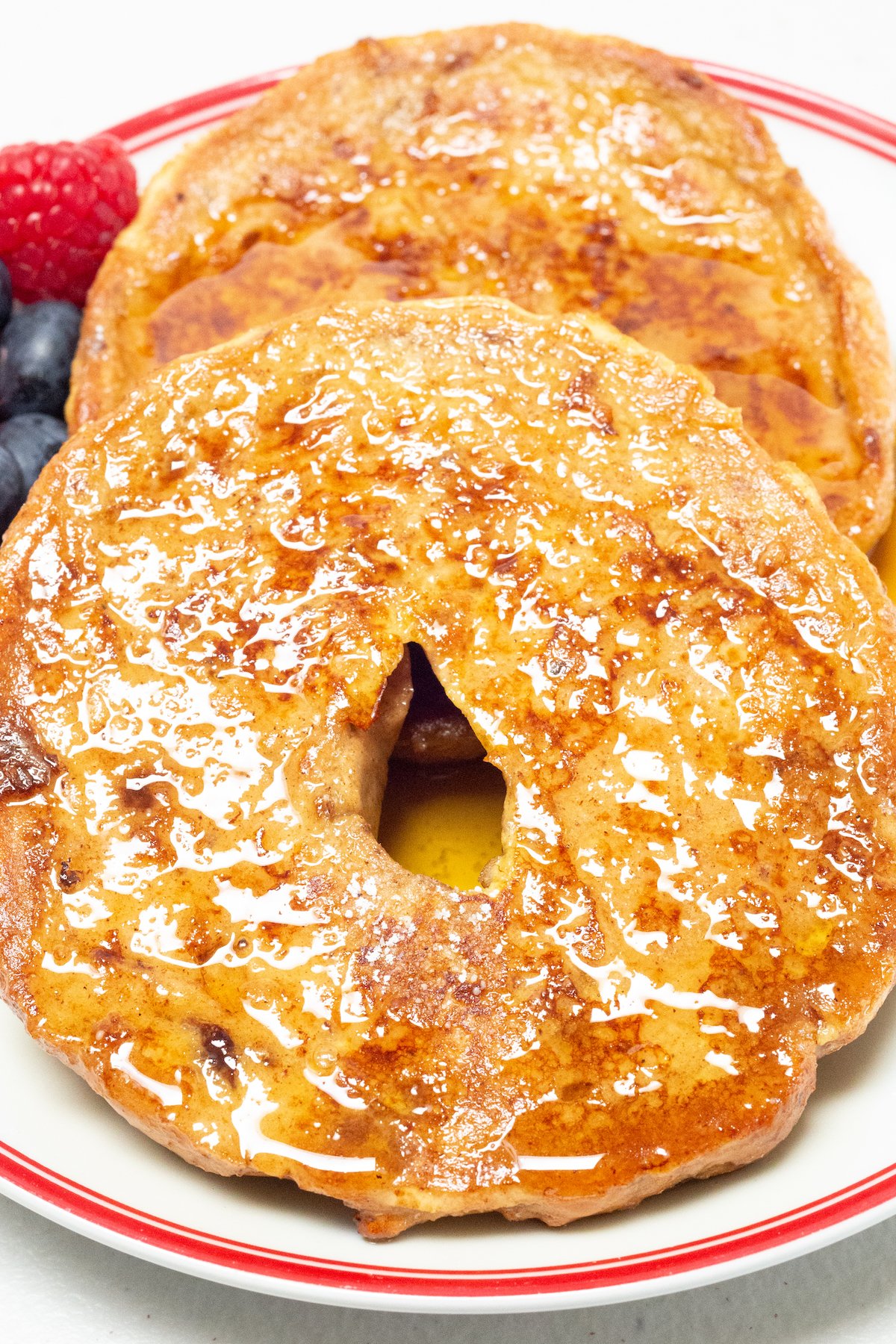 Two pieces of bagel that have been cooked like french toast sit on a plate.