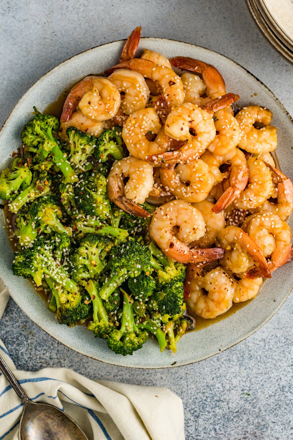 Overhead view of a dining plate that's half filled with cooked shrimp and the other half broccoli florets.