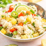 A serving bowl filled with instant pot coconut rice that has chopped pineapple, green onions, jalapenos, and red bell pepper.