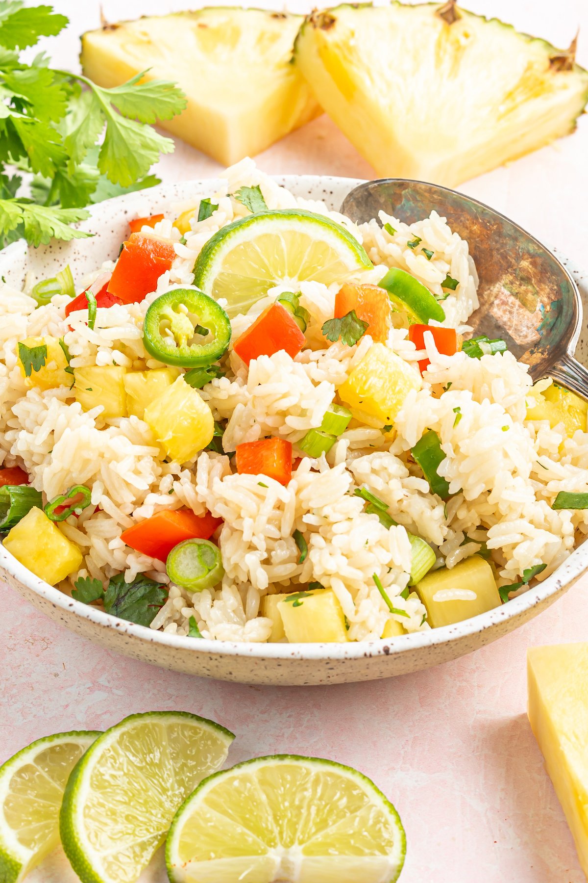 A serving bowl filled with instant pot coconut rice that has chopped pineapple, green onions, jalapenos, and red bell pepper.