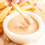 A french fry being dipped into homemade Zax sauce.
