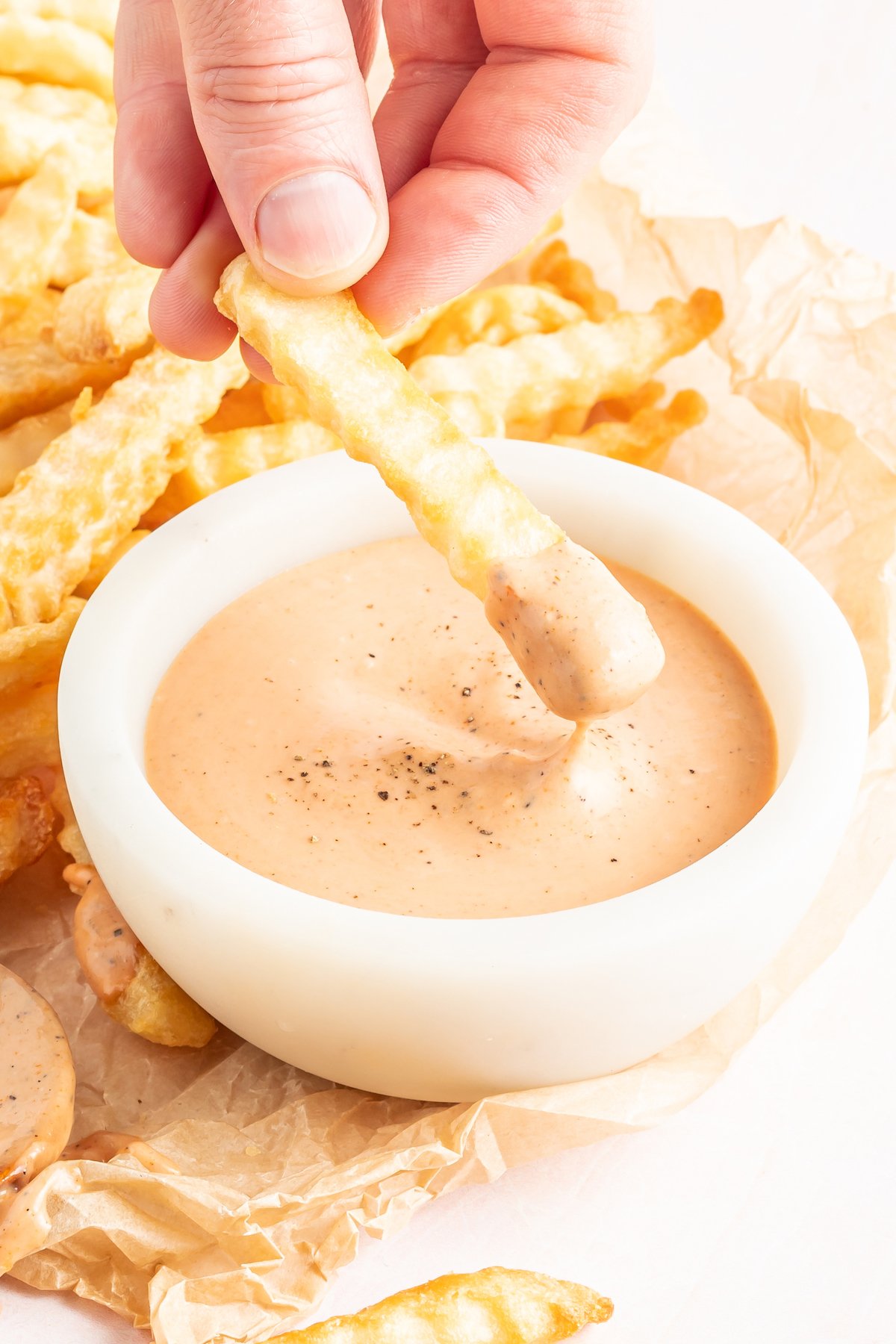 A french fry being dipped into homemade Zax sauce.