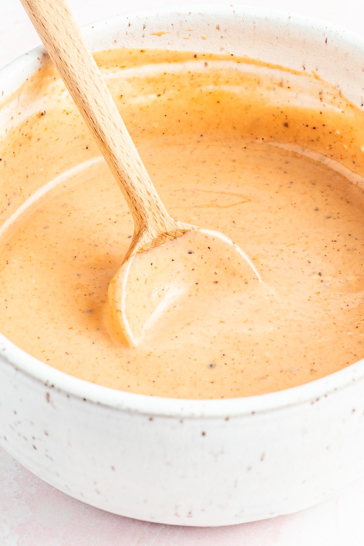 Copycat Zax sauce in a white bowl with a brown spoon.