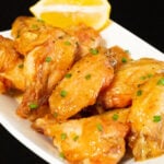 Glazed honey lemon pepper wings on a black background.