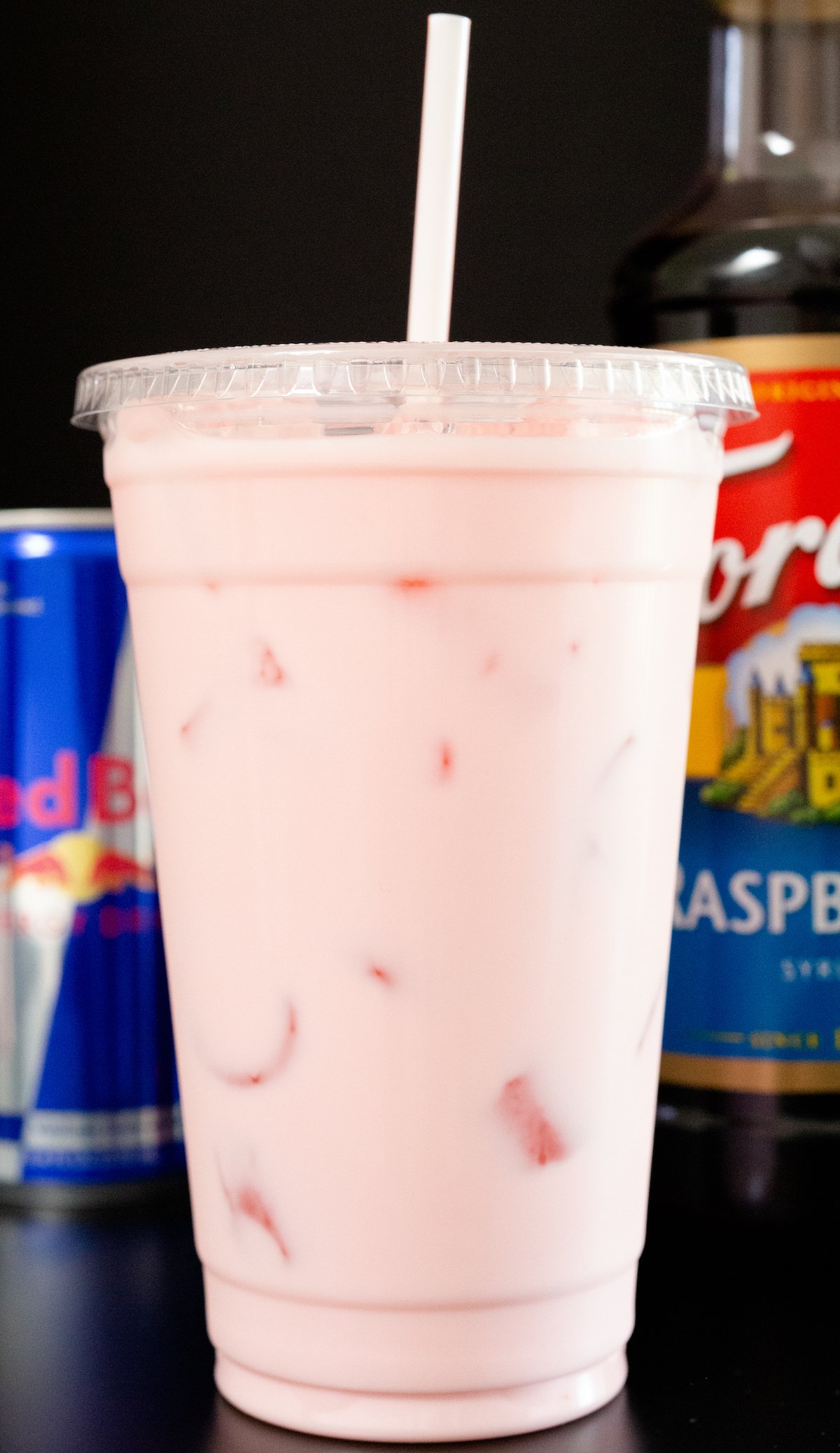 A large plastic cup is filled with a pink Red Bull Italian Soda.