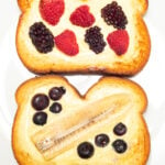 Two slices of air fryer custard toast filled with fresh berries and banana slices on a white dinner plate.