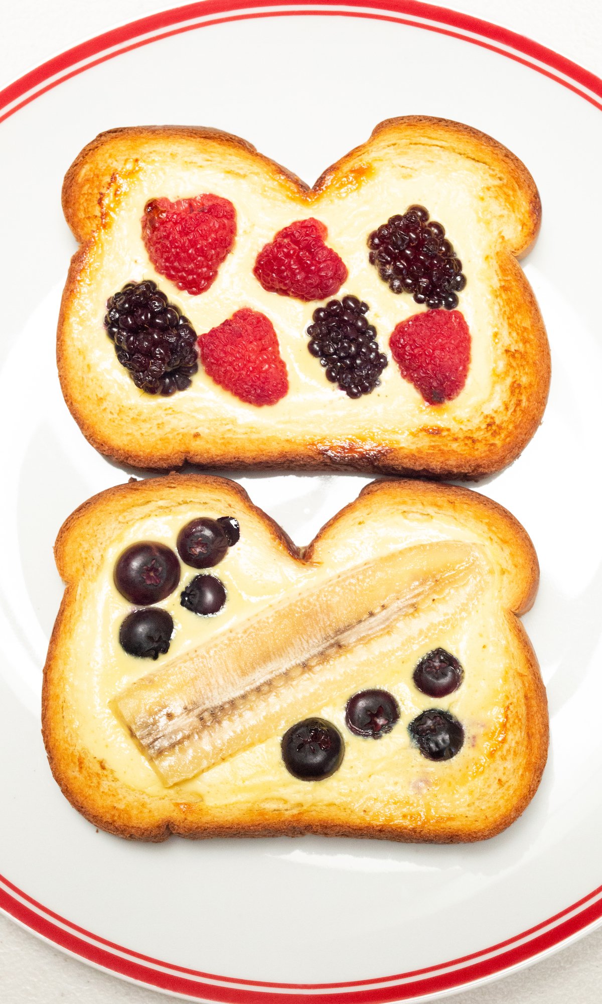 Two slices of air fryer custard toast filled with fresh berries and banana slices on a white dinner plate.