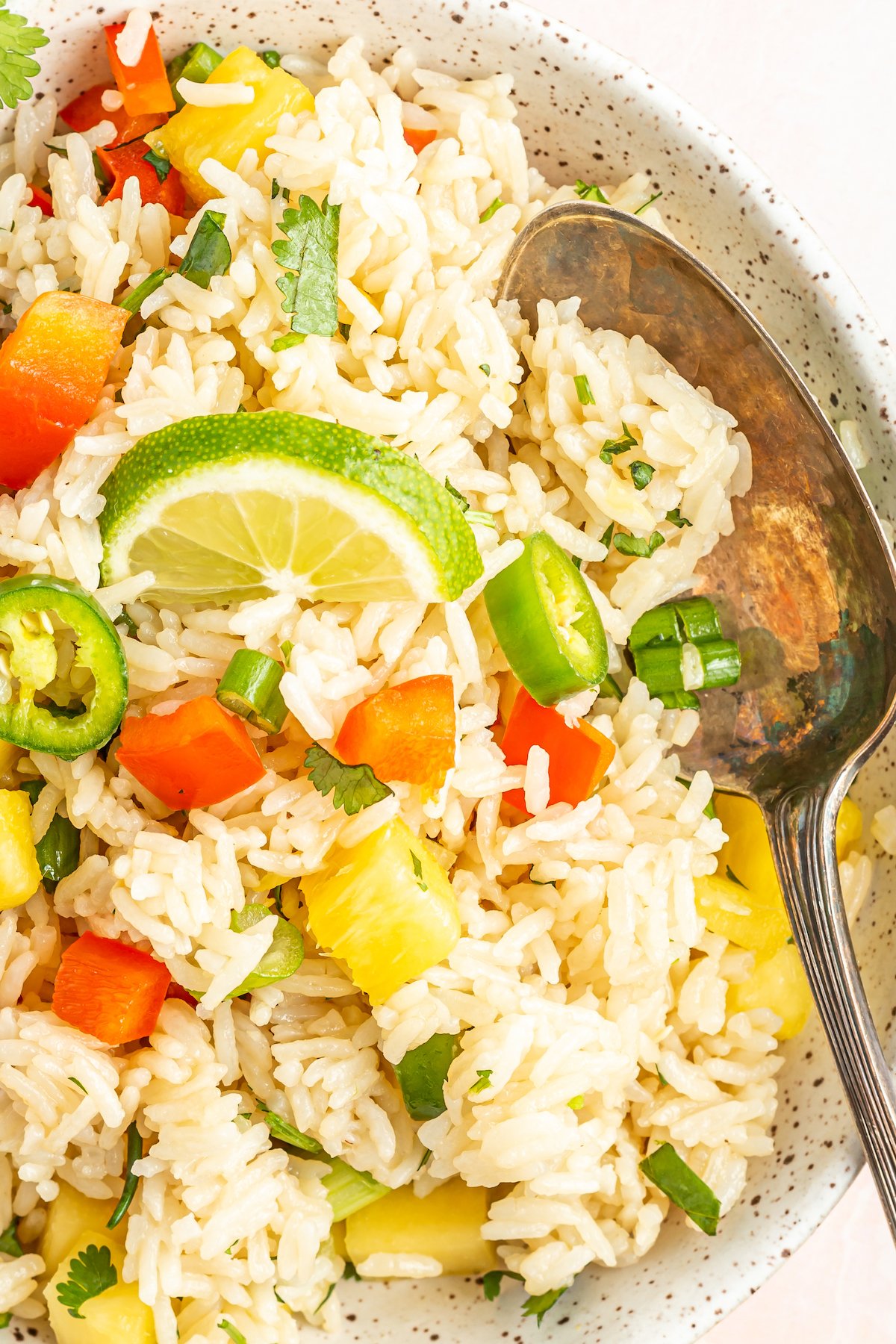 A serving bowl filled with white Instant Pot coconut rice with pineapple and peppers.