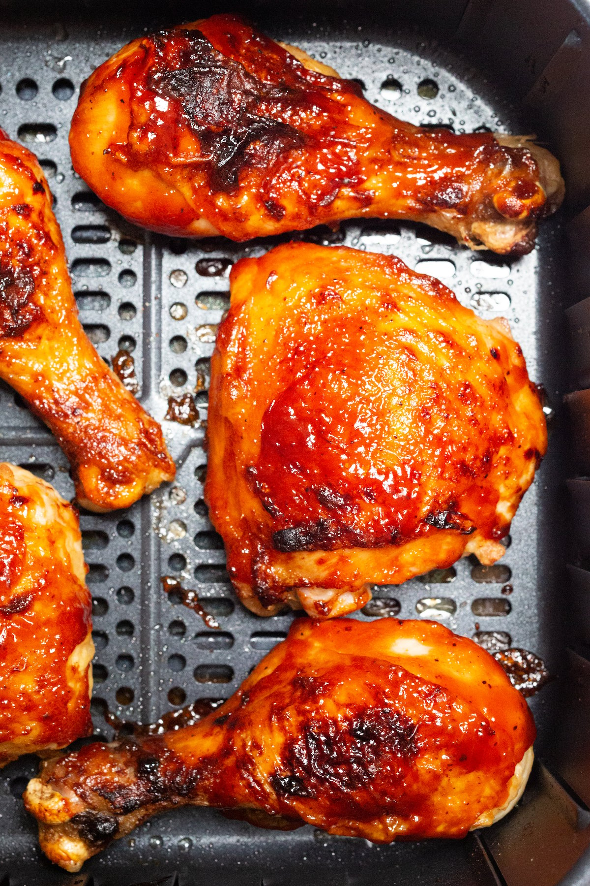 BBQ Chicken legs and thighs in an air fryer basket.