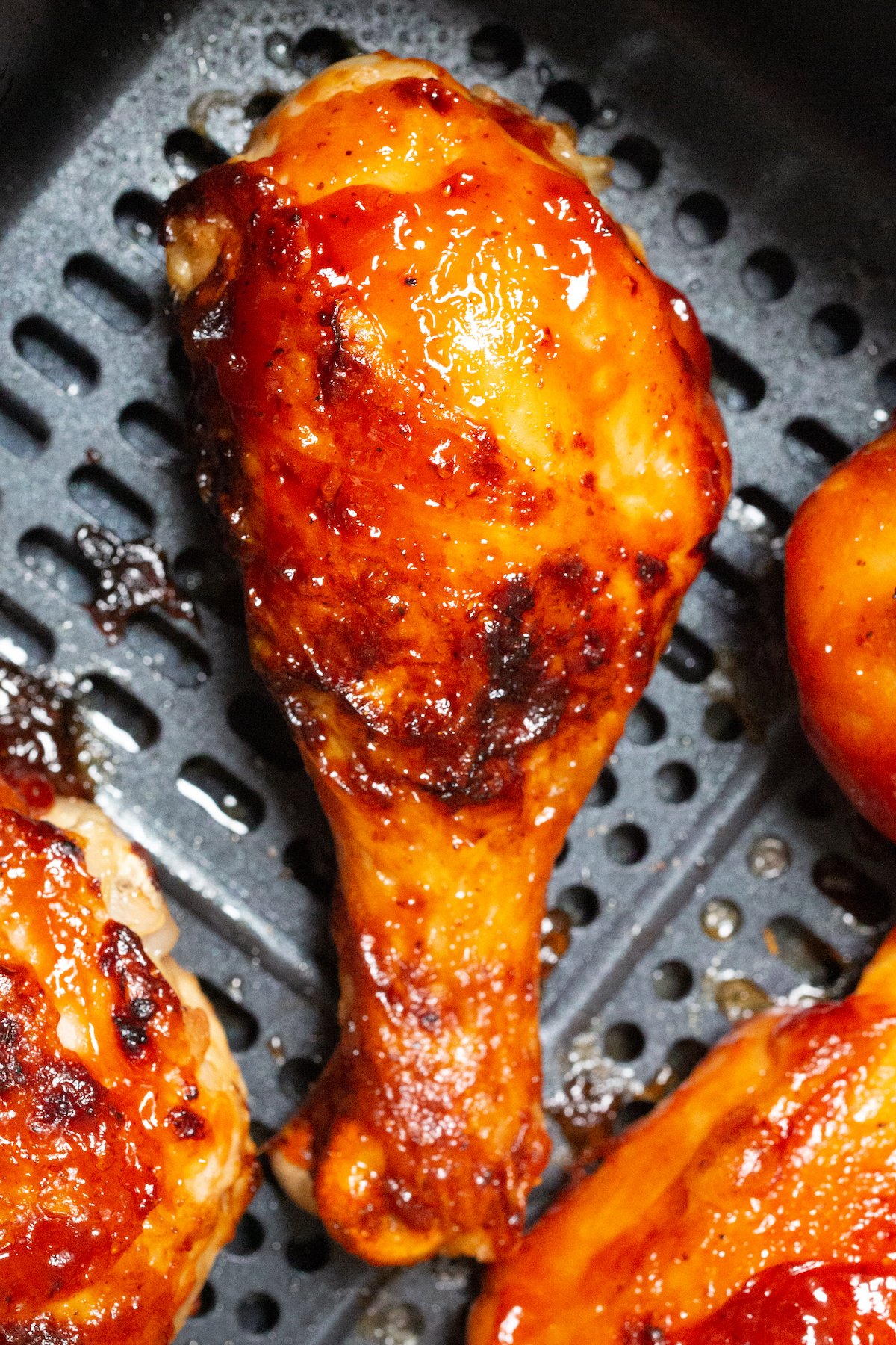 A BBQ chicken drumstick in an air fryer basket. 