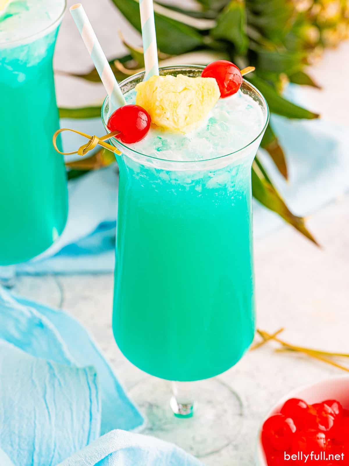 A tall glass filled with a vibrant blue Blue Hawaiian cocktail.