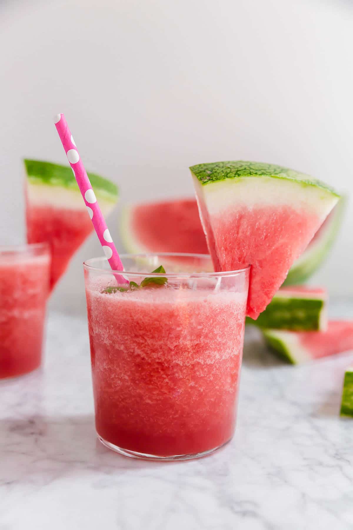 A short glass filled with Watermelon Frosé and garnished with a watermelon slice. 