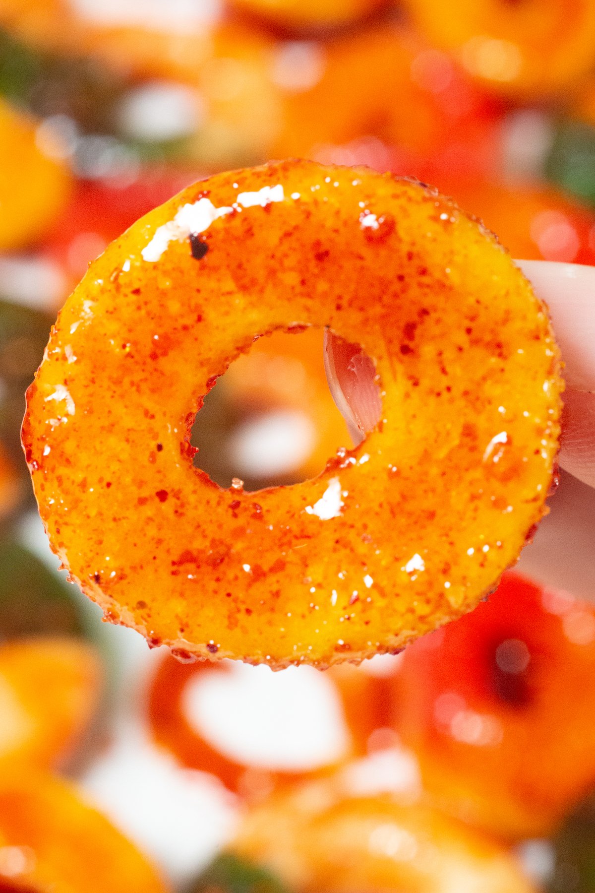 Close up of a hand hold a spicy Mexican peach ring gummy.
