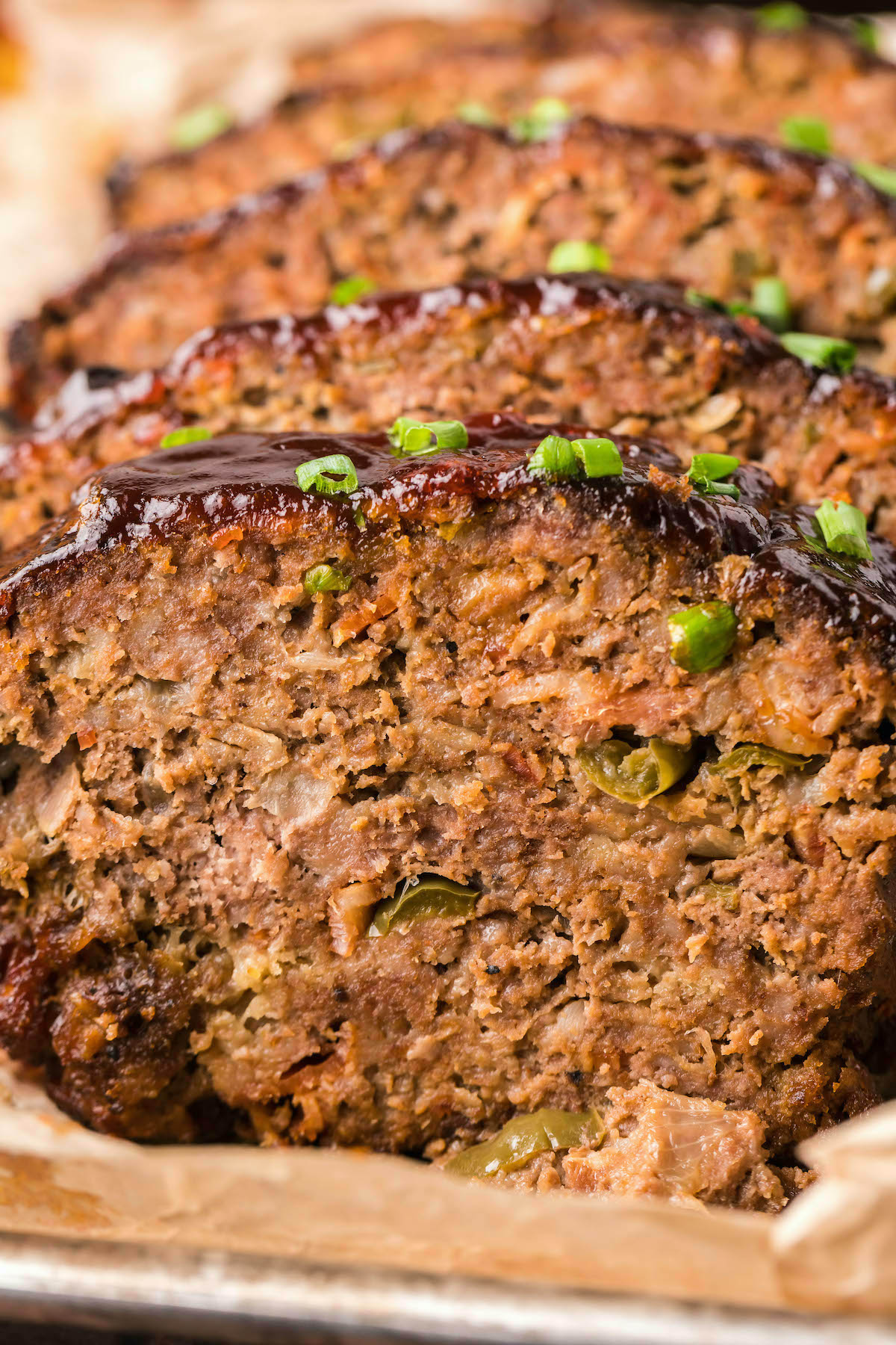 Closeup of four slices of BBQ meatloaf in a bread pan.