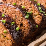 Slices of meatloaf topped with BBQ sauce and green onions.