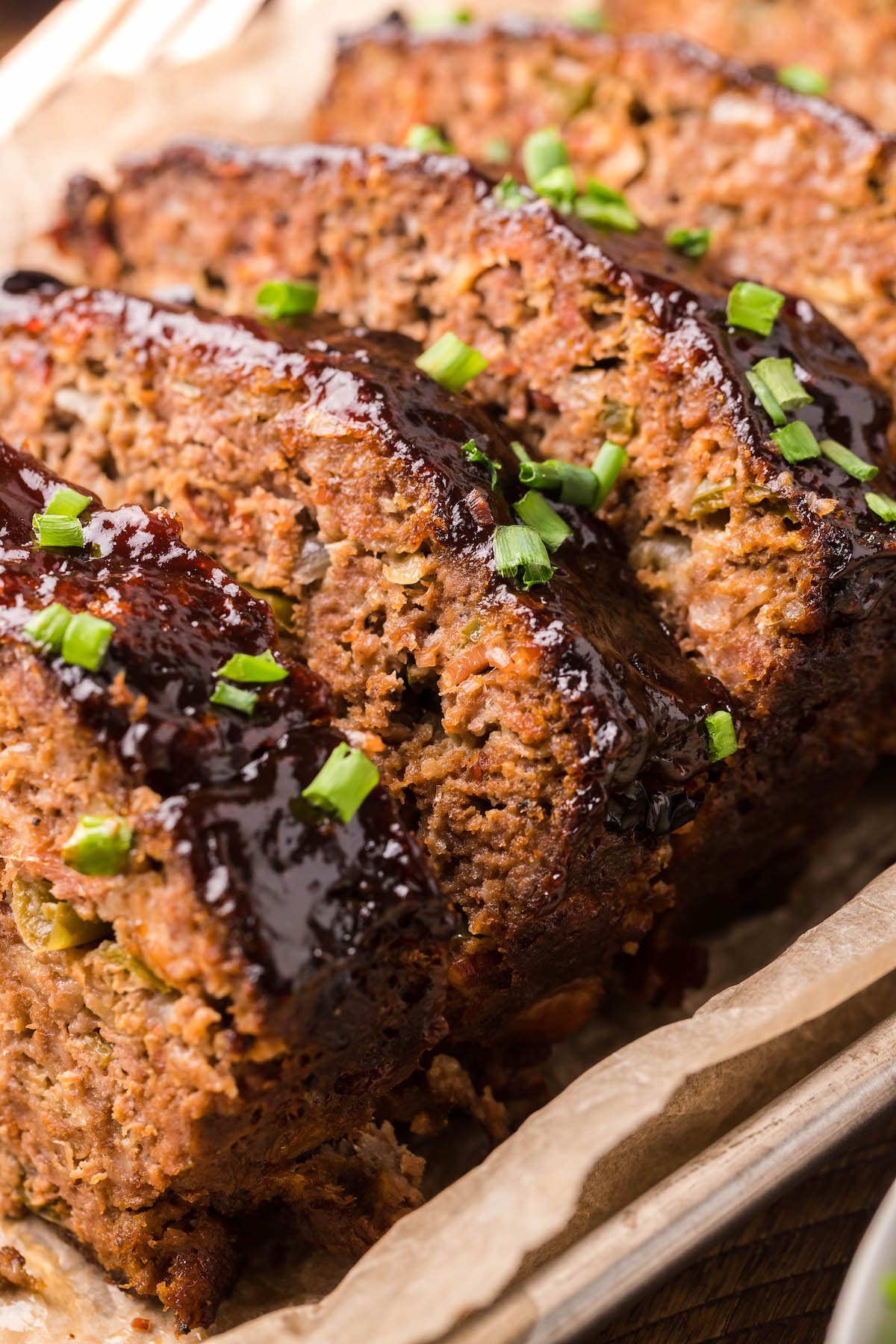 Slices of meatloaf topped with BBQ sauce and green onions.